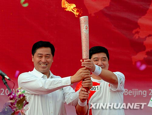 7月18日,第一棒火炬手王义夫(右)从鞍山市委书记张杰辉手中接过火炬。当日,北京奥运圣火在辽宁省鞍山市传递。 新华社记者谢环驰摄